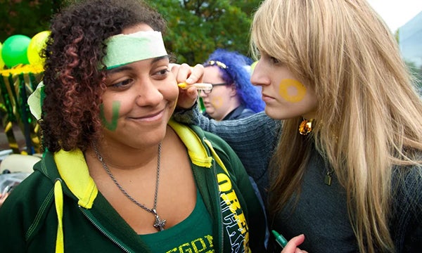 One student applying UO game makeup to another student